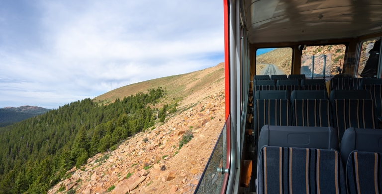 Train window on mountainside with green trees